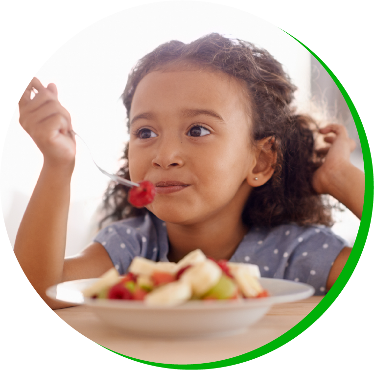 a little girl sitting at a table with a plate of food